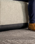 Person wearing brown shoes and blue jeans standing next to a textured gray ottoman. Kansas City Office Design.