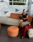 Two women sitting on a modern sofa with geometric wall design in the background. Kansas City Office Design.