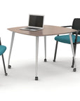 Square mobile sitting height table with a laptop on it, surrounded by chairs with teal seats and black frames, on a white background. Kansas City Office Design