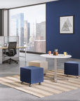 Modern office space with blue and beige ottomans, a white table, and cityscape view. Kansas City Office Design