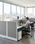 Modern office with employees working at their desks, large windows showing a cityscape. Kansas City Office Design