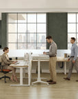 Modern office with people working at standing desks and large windows. Kansas City Office Design