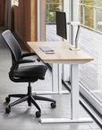 HumanScale eFloat Go 2.0 Sit-Stand Height Adjustable Desk in work from home office with natural light. Natural laminate top. White base. Kansas City office furniture.