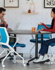 Two people sitting at a table in a modern office setting, engaged in conversation. Kansas City Office Design.