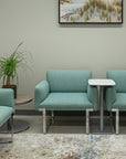 Modern waiting room with teal SitOnIt Cameo chairs and a small table, featuring a nature-themed painting on the wall. Kansas City Office Design