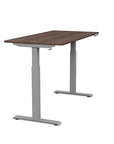 Side view of the SitonIt Switchback Height Adjustable Sit-to-Stand Desk. It has a Silver base with a 27"D x 54"W Walnut top - Kansas City Office Furniture
