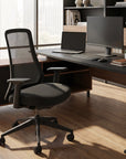 Modern office desk with chair, computer setup, and decor in a bright room. Kansas City Office Design.
