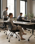 Modern office space with people working at desks near large windows. Kansas City Office Design.