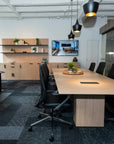 Modern office space with a long wooden table, AIS Auburn Conference chairs, and a TV on the wall. Kansas City Office Design