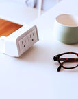 SitOnIt clamp on EON Power with dual outlets on a desk next to a mug and glasses. Kansas City Office Design.