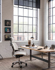 Modern office setup with a desk, Humanscale Freedom chair, and large windows. Kansas City Office Design.
