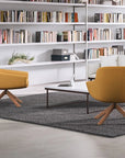 Modern living room with two yellow SitOnIt Gobi lounge chairs with wood legs, a coffee table, and a bookshelf filled with books. Kansas City Office Design.