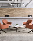 Modern interior with orange Gobi lounge chairs and a coffee table in front of a brick wall. Kansas City Office Design.