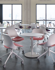 Modern cafe setup with white and red Humanscale Trea chairs around Humanscale Float Gather 30" round tables in a large room with large windows. Kansas City Office Design.