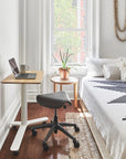 Small home office with a Humanscale Float Mini standing desk, Humanscale saddle chair, and laptop in a bedroom setting. Kansas City Office Design.