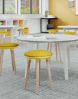 Round table with Via Joi low stools in yellow fabric in a classroom setting. Kansas City Office Design.