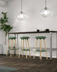 Three green Via Joi bar stools with wooden legs in front of a bar counter in a modern room. Kansas City Office Design.
