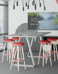Modern office space with a table and Via Joi red stools, featuring a digital clock on the wall. Kansas City Office Design.
