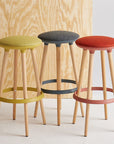 Three Via Joi bar stools with colorful seats against a wooden and white background. Kansas City Office Design.