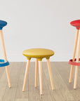 Three colorful Via Joi stools on a wooden floor with a plain background. Kansas City Office Design.
