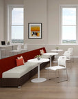 Modern office break room with red and white furniture, large windows, and a framed picture on the wall. Kansas City Office Design
