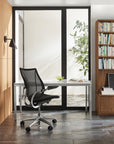 Modern office setup with a black Humanscale Liberty chair, desk, and bookshelf. Kansas City Office Design.