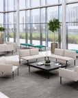 Modern office lounge area with beige SitOnIt Cameo sofas, coffee tables, and large windows. Kansas City Office Design