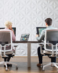 Two people sitting at a desk with computers in an office setting. Kansas City Office Design