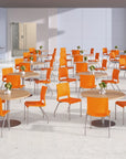 Modern cafeteria with orange chairs and round tables in a bright room. Kansas City Office Design.