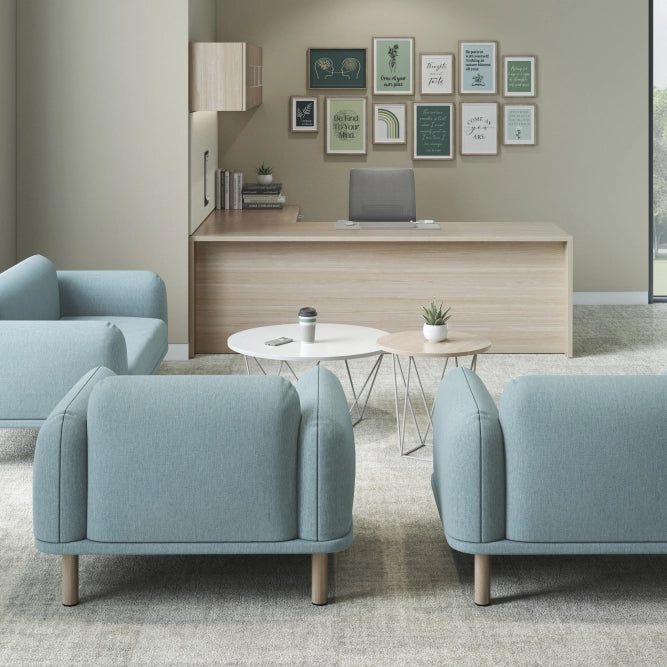 Modern office space with light blue chairs, a desk, and framed pictures on the wall. Kansas City Office Design.