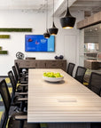 Modern conference room with a large table, chairs, and a screen displaying a presentation. Kansas City Office Design.