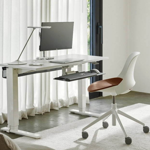 Modern office setup with a adjustable desk, chair, and computer monitor. Kansas City Office Design