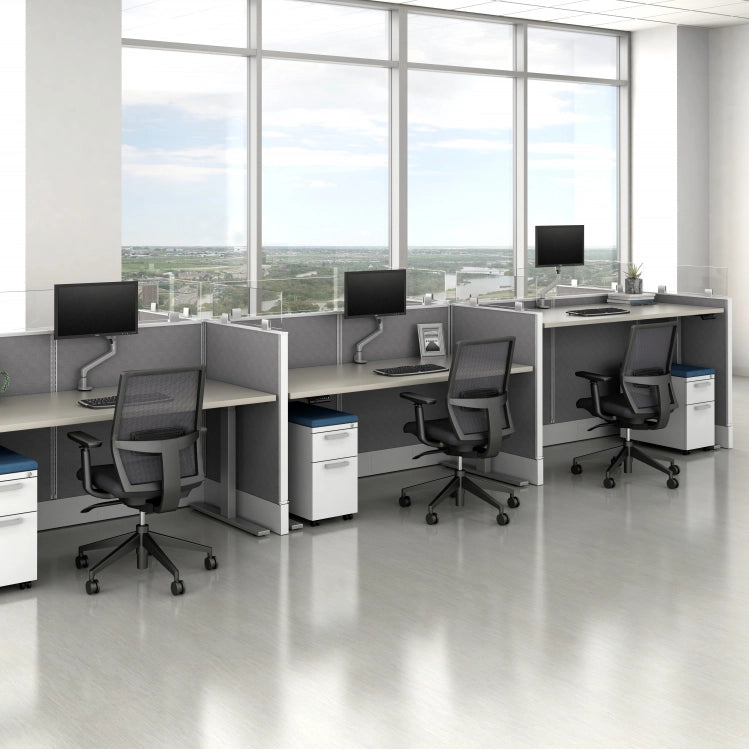 Modern office setup with desks, chairs, and computer monitors in a bright room with large windows. Kansas City Office Design