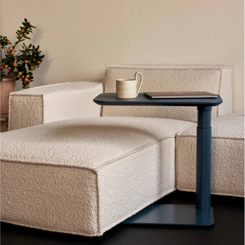 Beige sofa with a Humanscale float micro in Slate Blue holding a mug and a laptop, against a neutral wall. Kansas City Office Design.