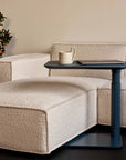 Beige sofa with a Humanscale float micro in Slate Blue holding a mug and a laptop, against a neutral wall. Kansas City Office Design.