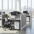 Modern office setup with cubicles/workstations, chairs, and cityscape view. Kansas City Office Design.