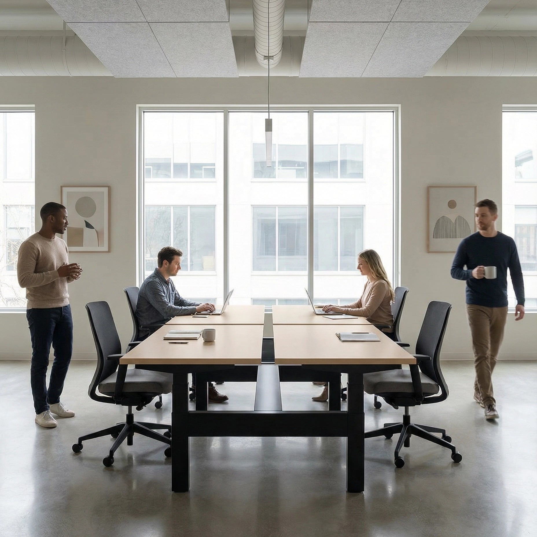 HAT Collective Height adjustable 4pod with black base and maple tops with people working in an open office. Kansas City Office Design