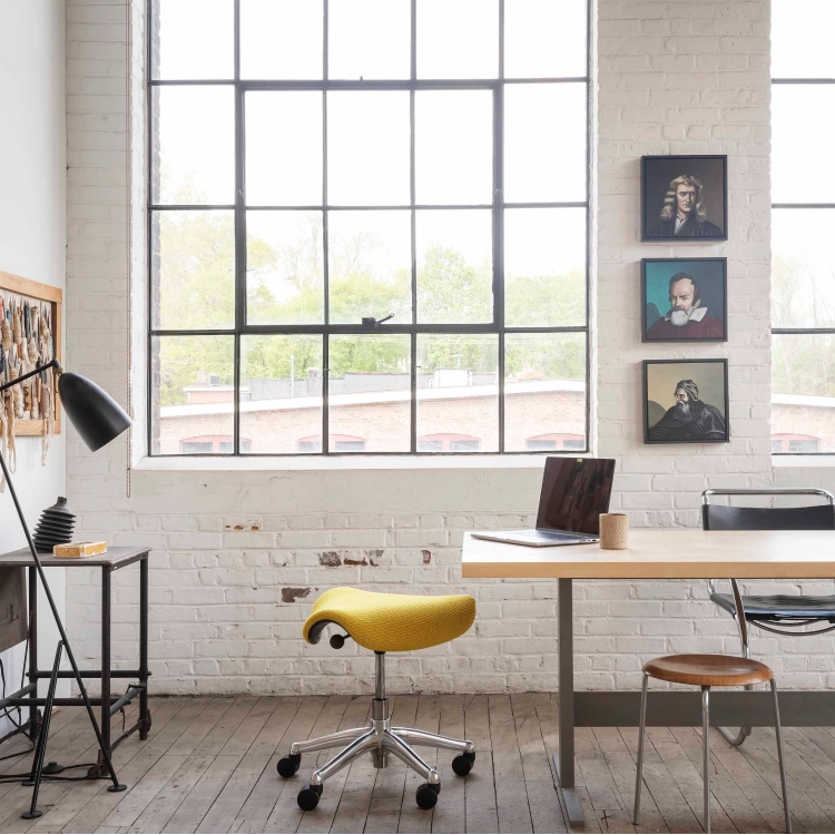 Humanscale saddle stool in a modern office space with a desk, chairs, and large windows. Kansas City Office Design.