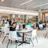 People sitting in the Rio 4Leg Stacking chair at tables in a modern, well-lit indoor setting. Kansas City Office Design.