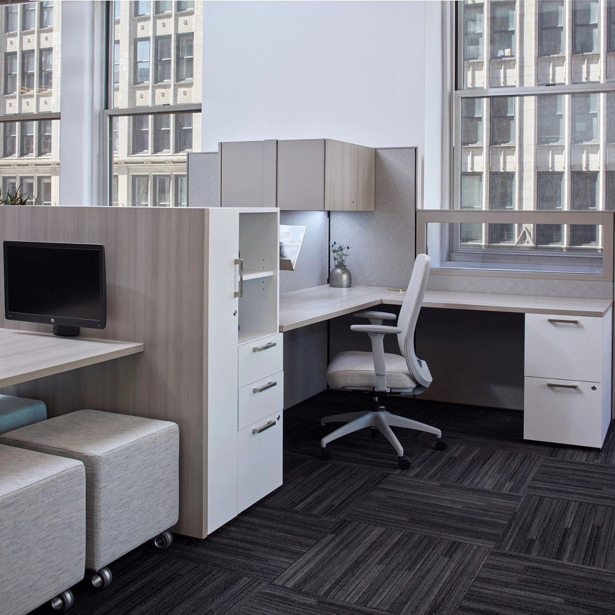 Modern office cubicle with desk, chair, and cabinets in a cityscape setting. Kansas City Office Design
