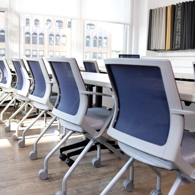 Row of blue and gray chairs in a modern office setting with large windows. Kansas City Office Design.