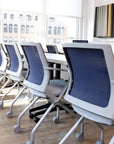 Row of blue and gray chairs in a modern office setting with large windows. Kansas City Office Design.