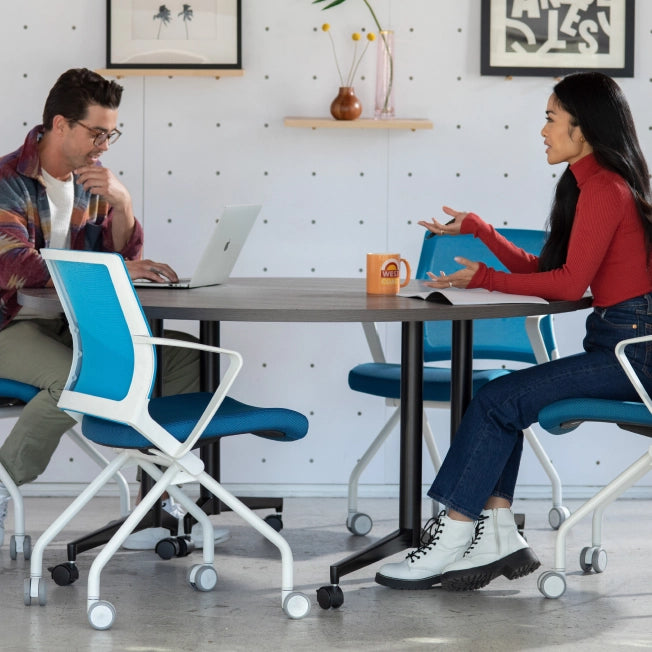 Two people sitting at a table in a modern office setting, engaged in conversation. Kansas City Office Design.