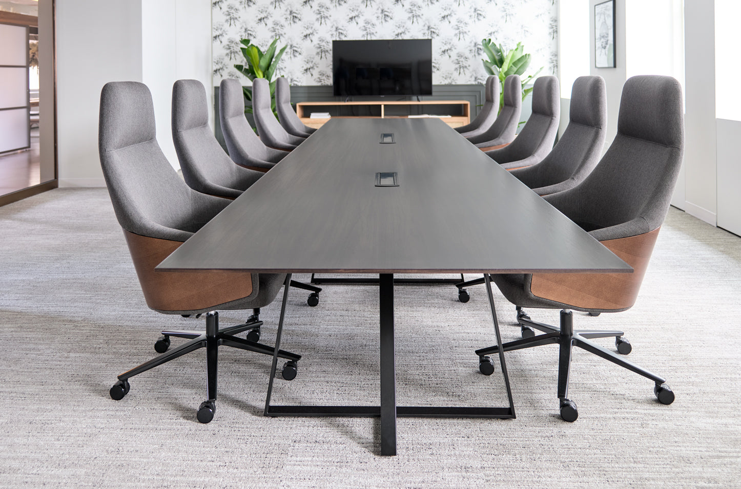 Modern conference room with a long gray table and gray chairs with brown accents. Kansas City Office Design