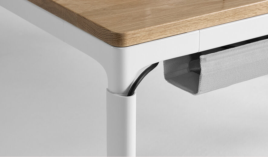 Close-up of a cable management on a Humanscale eFloat Quattro desk with a wooden top and white legs. Kansas City Office Design.