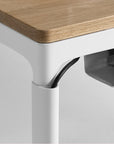 Close-up of a cable management on a Humanscale eFloat Quattro desk with a wooden top and white legs. Kansas City Office Design.