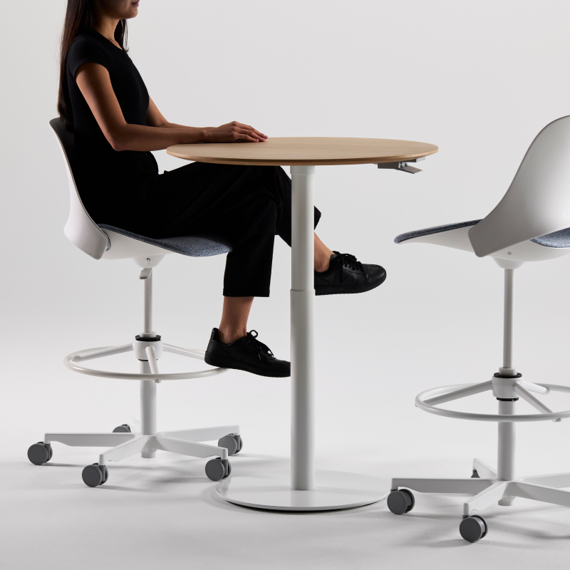 Person sitting at a modern table with white chairs on a plain background. Kansas City Office Design