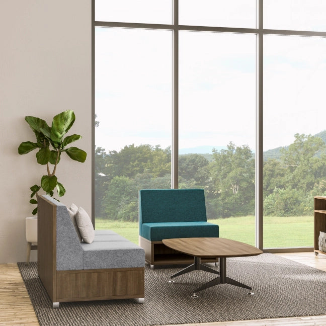 Modern office furniture with a blue chair, gray sofa, and coffee table in front of large windows with a view of greenery. Kansas City Office Design