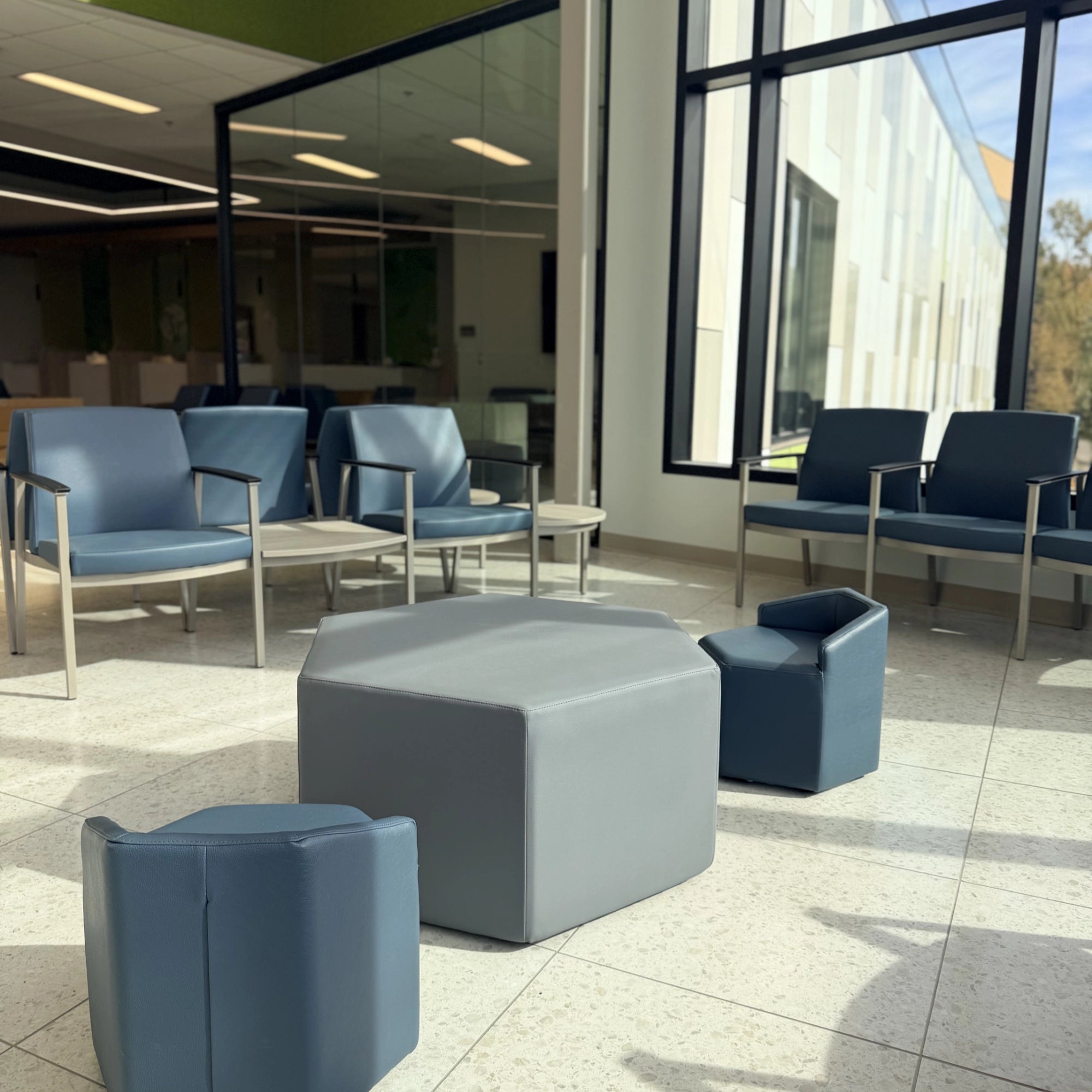 Modern office waiting area with OFS blue chairs and a gray ottoman. Kansas City Office Design.