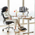 Person sitting at a modern desk with ergonomic chair and Humanscale footrest in a bright room. Kansas City Office Design.